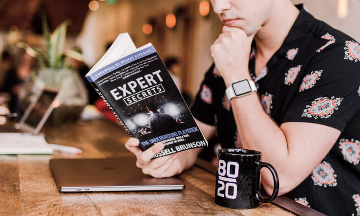 Person reading Expert Secrets book